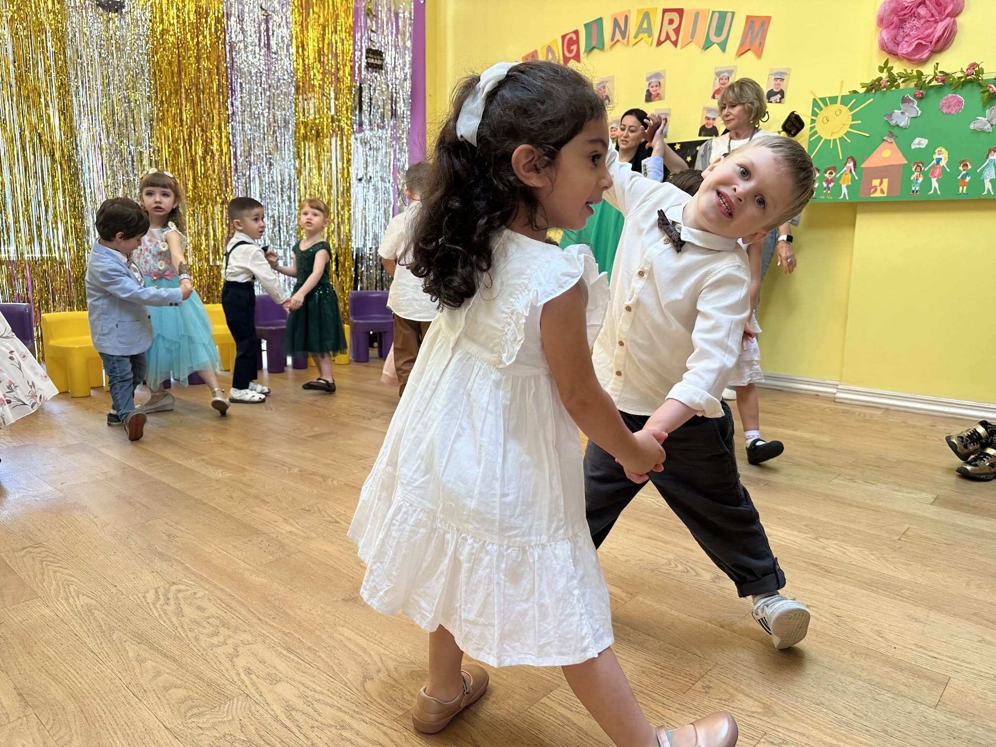 Children dancing at an Imaginarium celebration in our bright yellow classroom with the Imaginarium banner